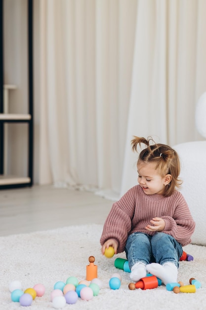 Cute little toddler girl playing at home with eco wooden toys Happy child cutting vegetables and fruits with toy knife The child playing educational games