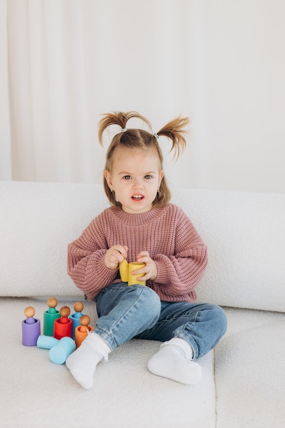 Cute little toddler girl playing at home with eco wooden toys Happy child cutting vegetables and fruits with toy knife The child playing educational games