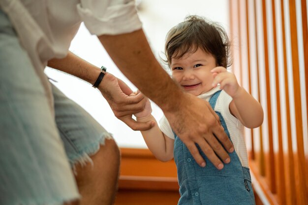 Cute little toddler holding toy while sitting on floor with stuff toy playing with father at home