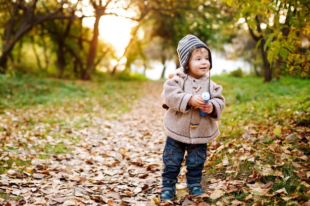 Piccolo bambino sveglio che sta nelle foglie di caduta