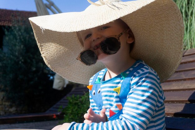 写真 特大の日よけ帽と太陽の下でリラックスしたサングラスを身に着けているかわいい幼児