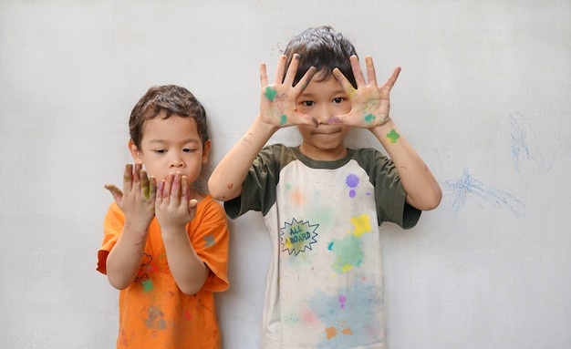 かわいい小さな2つのアジアの男の子の兄弟は、活動創造性の時間で楽しい色を再生します