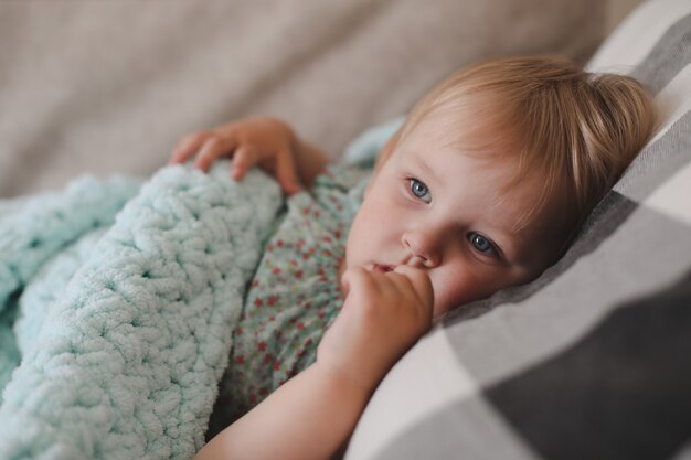 家で格子縞の下に横たわっているかわいい小さな2歳の女の子