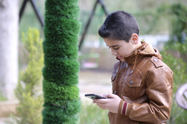 屋外の森の公園で歩いている可愛い小さな少年