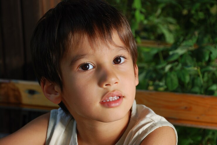 Cute male child is sitting outdoor, closeup
