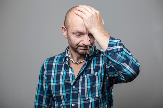 Cute man has headache putting his hand to his forehead and closed his eyes