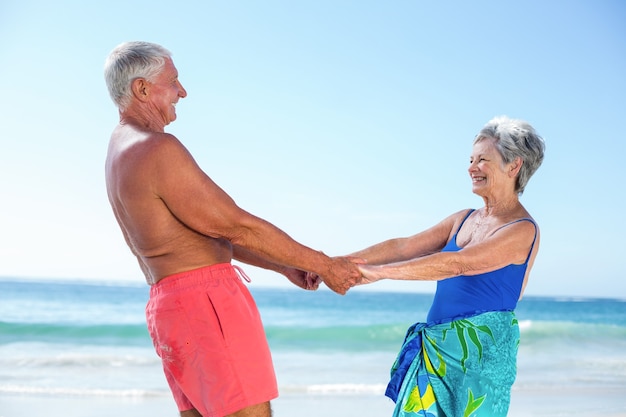 Cute mature couple holding hands on the beach