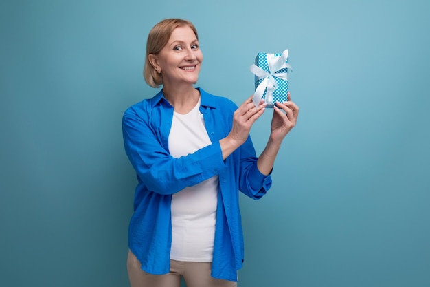 Cute middle aged woman received birthday present on blue background copy space