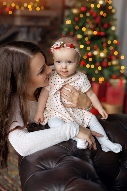 Cute mom and daughter on a blurry background with a Christmas tree