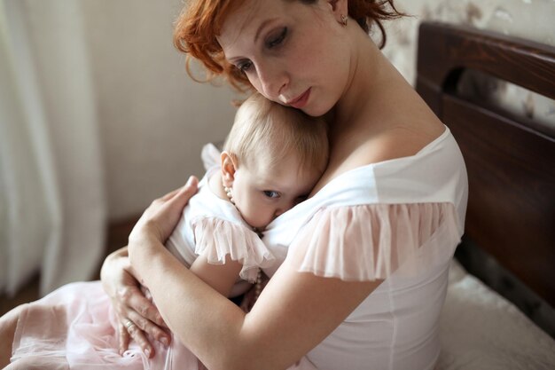 Foto cucina madre allattamento al seno bambina figlia su un letto in una stanza casual reale il concetto di tenerezza