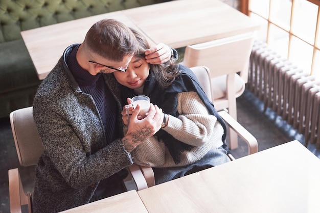 Cute multiracial couple sitting together in cafe. Asian girl with her caucasian boyfriend.