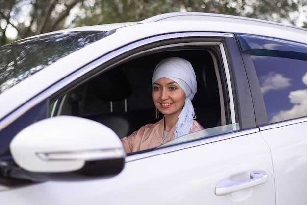 かわいいイスラム教徒の女性が現代の車に座っています。