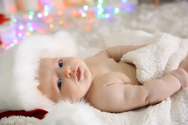 Cute naked baby in red hat on the warm blanket, close up