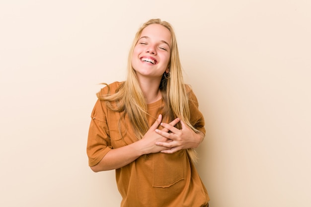 Cute and natural teenager woman laughing keeping hands on heart, concept of happiness.