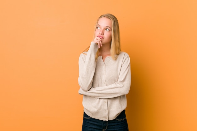 Cute and natural teenager woman looking sideways with doubtful and skeptical expression.