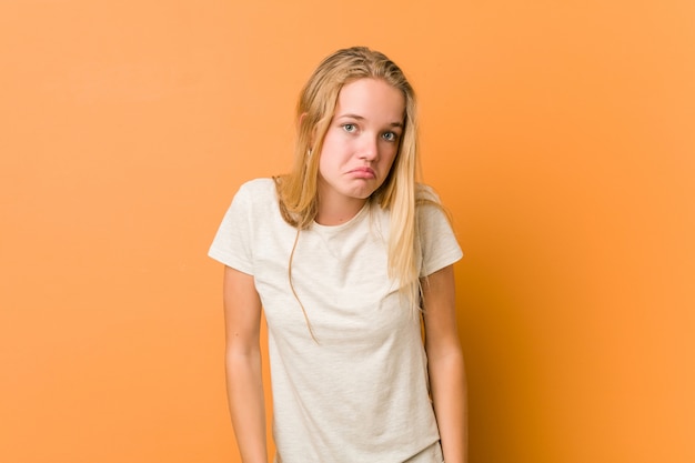 Photo cute and natural teenager woman shrugs shoulders and open eyes confused.