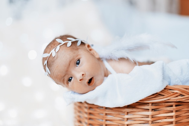 Photo cute newborn baby angel looking out of the baby basket