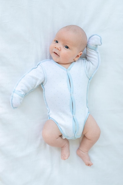 写真 赤ちゃんの週に就寝する前に、自宅の綿のベッドのベビーベッドの後ろに横たわっているかわいい新生児の男の子誕生と幼児期のトップビューの概念