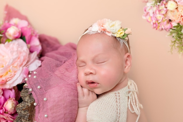 Photo cute newborn baby in a dress newborn girl in flowers newborns first photo session