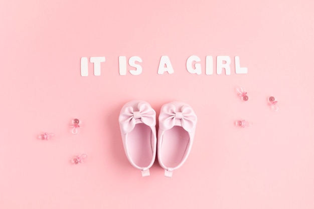ピンクの壁にお祝いの装飾が施されたかわいい新生児の女の子の靴。