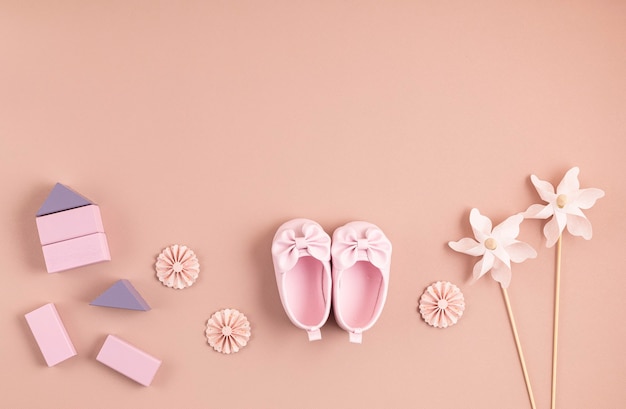 Cute newborn baby girl shoes with festive decoration over pink wall. 