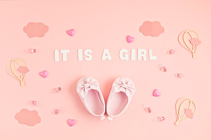 Photo cute newborn baby girl shoes with festive decoration over pink wall. 