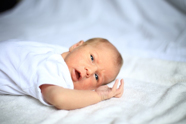 Cute newborn baby lying peacefully in the crib .