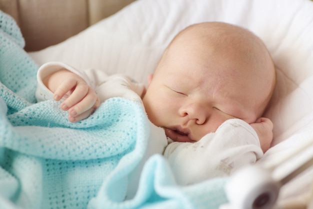 ベビーベッドで眠っているかわいい新生児