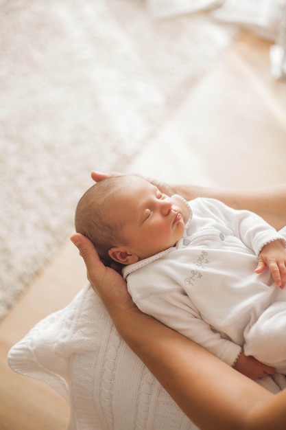 Cute newborn baby sleeping in mother's arms. Motherhood.