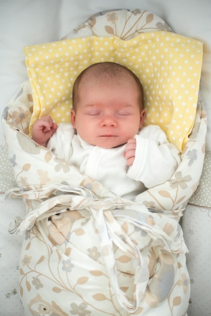 Cute newborn baby sleeping in swaddle wrap with smile on her face