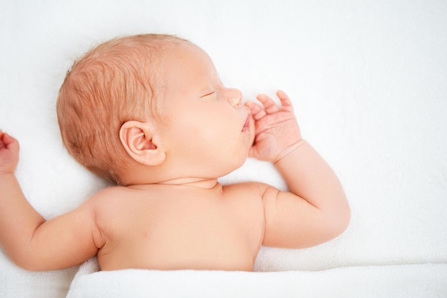 Cute newborn baby sleeps in white