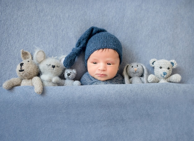 Cute newborn boy lying under blue blanket