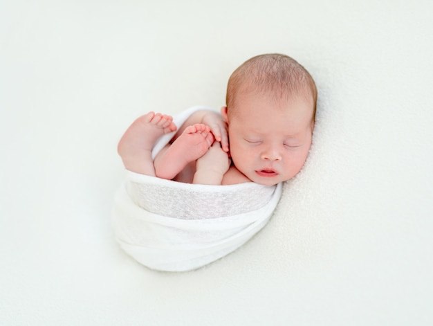 Cute newly arrived baby lying, wrapped in blanket