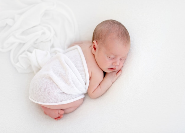 Cute newly arrived baby lying, wrapped in blanket