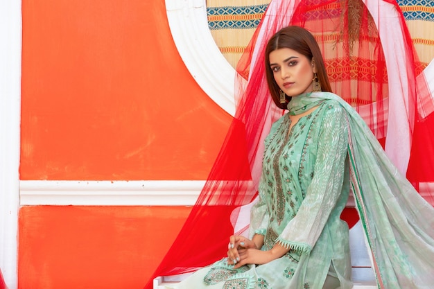 Cute Pakistani Girl Landscape Sitting on Table Wearing Floral Desi Dress for Fashion Photoshoot