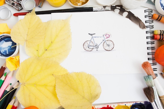 Cute pictured bicycle with autumn leaves flat lay