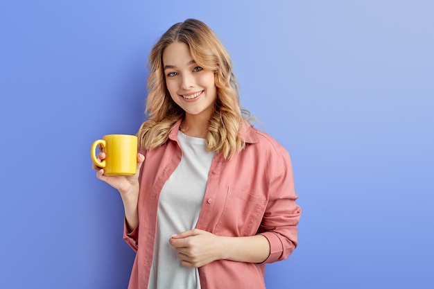 Cute positive girl drinking coffee or tea in morning before school or university