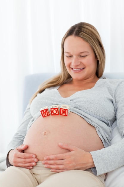かわいい妊娠している妻は、彼女の腹の母親の文字を見て
