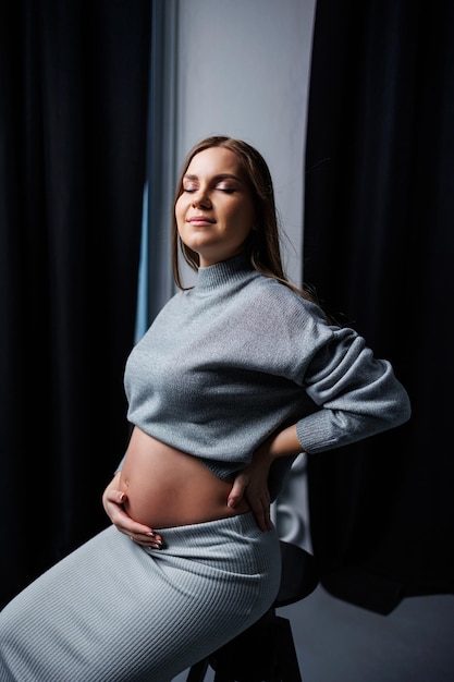 Cute pregnant woman in sweater and skirt with tummy Happy elegant pregnant woman A woman is expecting a child