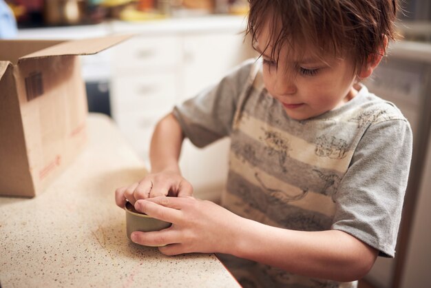 Cute preschool boy opening a tin in the kitchen at home during a quarantine