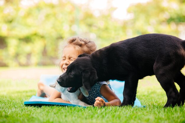 Cute preschool girl play with pets on fresh grass