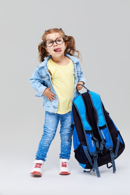  Cute preschool girl with a blue backpack on her back, holding a globe in her hands