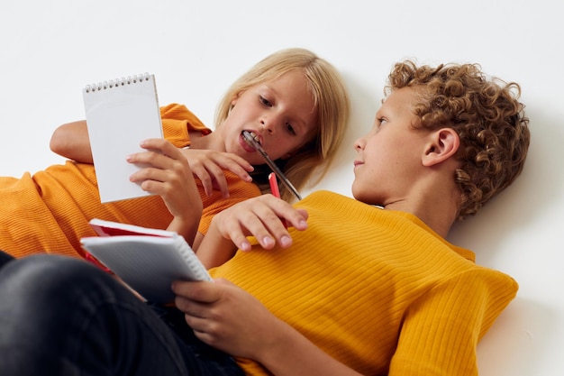 Cute preschool kids drawing in notebooks lying on the floor isolated background unaltered