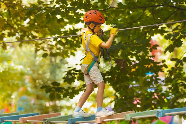 Il simpatico bambino in età prescolare sta giocando nel parco avventura