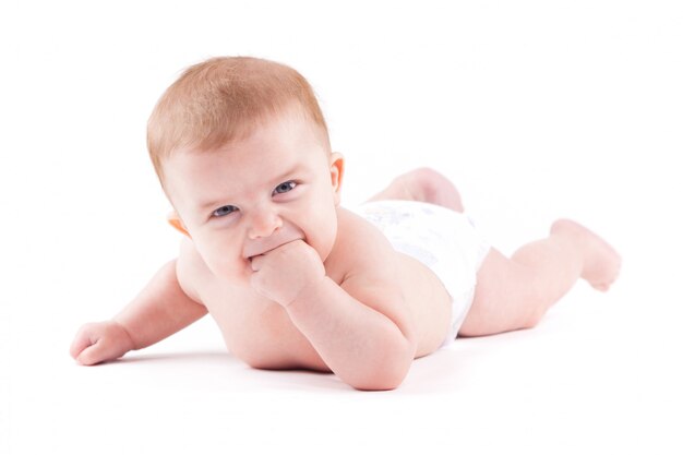 Cute pretty little boy in white diaper lies on belly