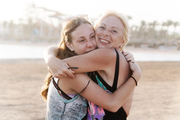 Figlia abbastanza teenager sveglia con la madre matura che abbraccia in natura al tramonto