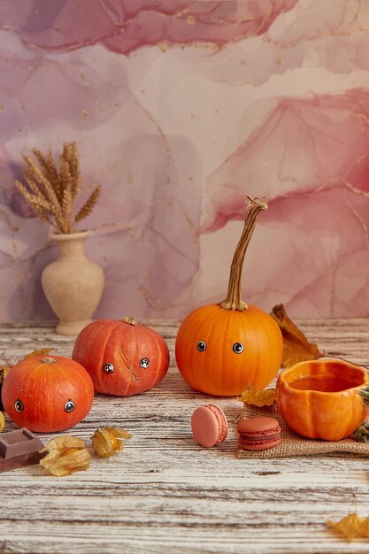 Cute pumpkins with eyes halloween seasonal funny family among\
macaroons and cup of tea thanksgiving decorations at cozy home