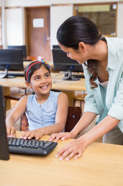 Cute pupil in computer class with teacher