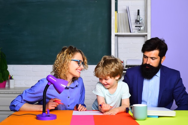 Allievo carino e suo padre e sua madre nell'istruzione scolastica di settembre in classe pronti a studiare felici