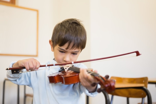 Симпатичный ученик, играющий на скрипке в классе